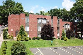 The front of a brick building with grass and trees